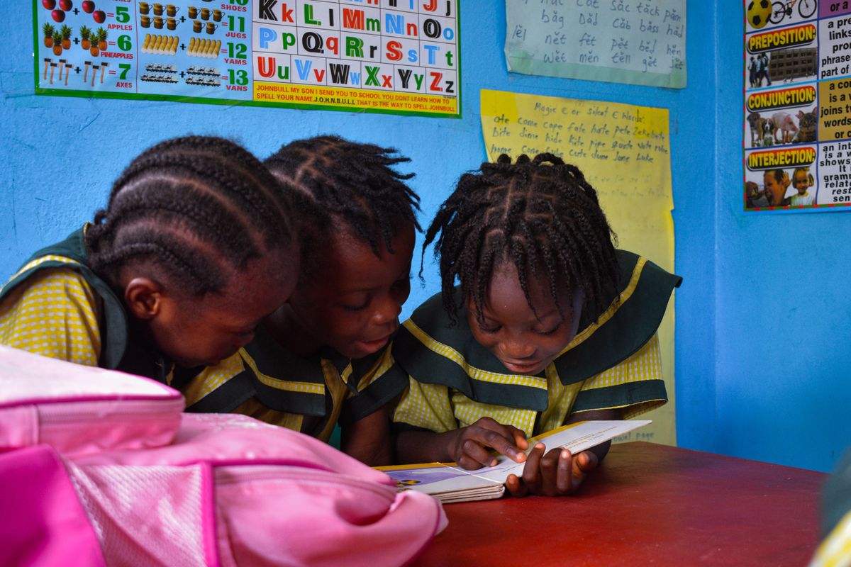 Young pupils in school uniform reading together at a desk