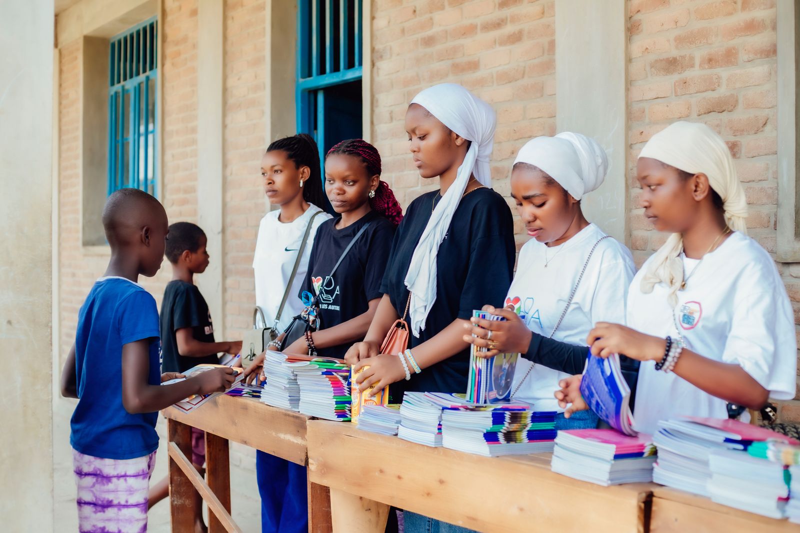 Volunteers distributing notebooks and school supplies to a pupil