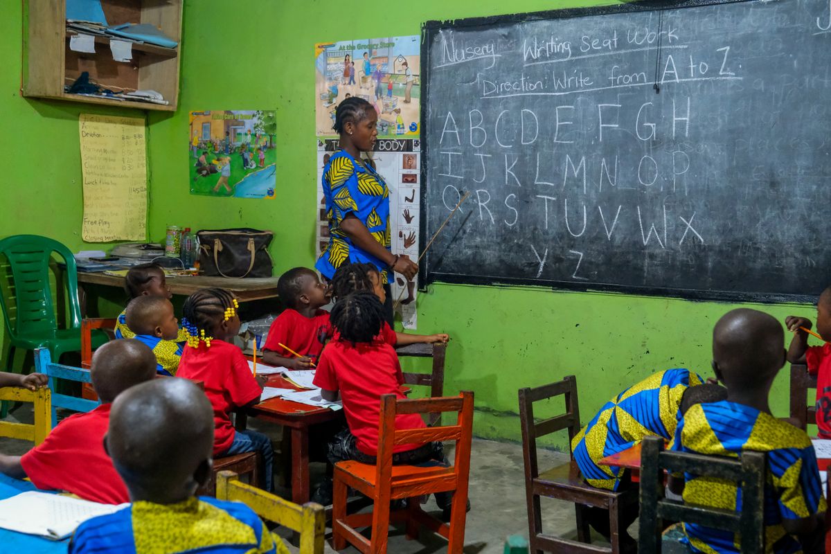 A teacher working with young pupils at a classroom chalkboard